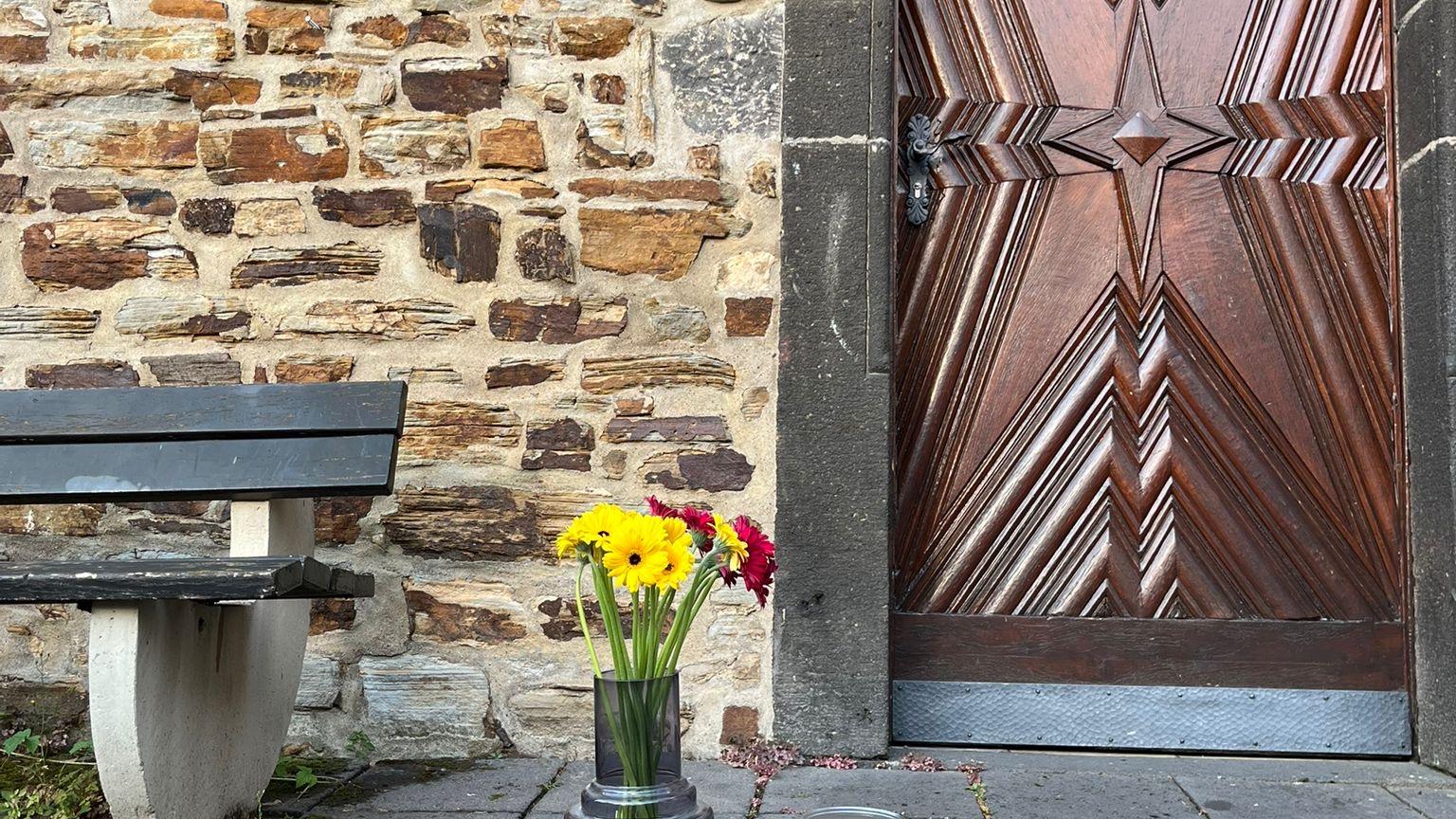 Blumenstrauß steht auf dem Boden vor Kirchentür