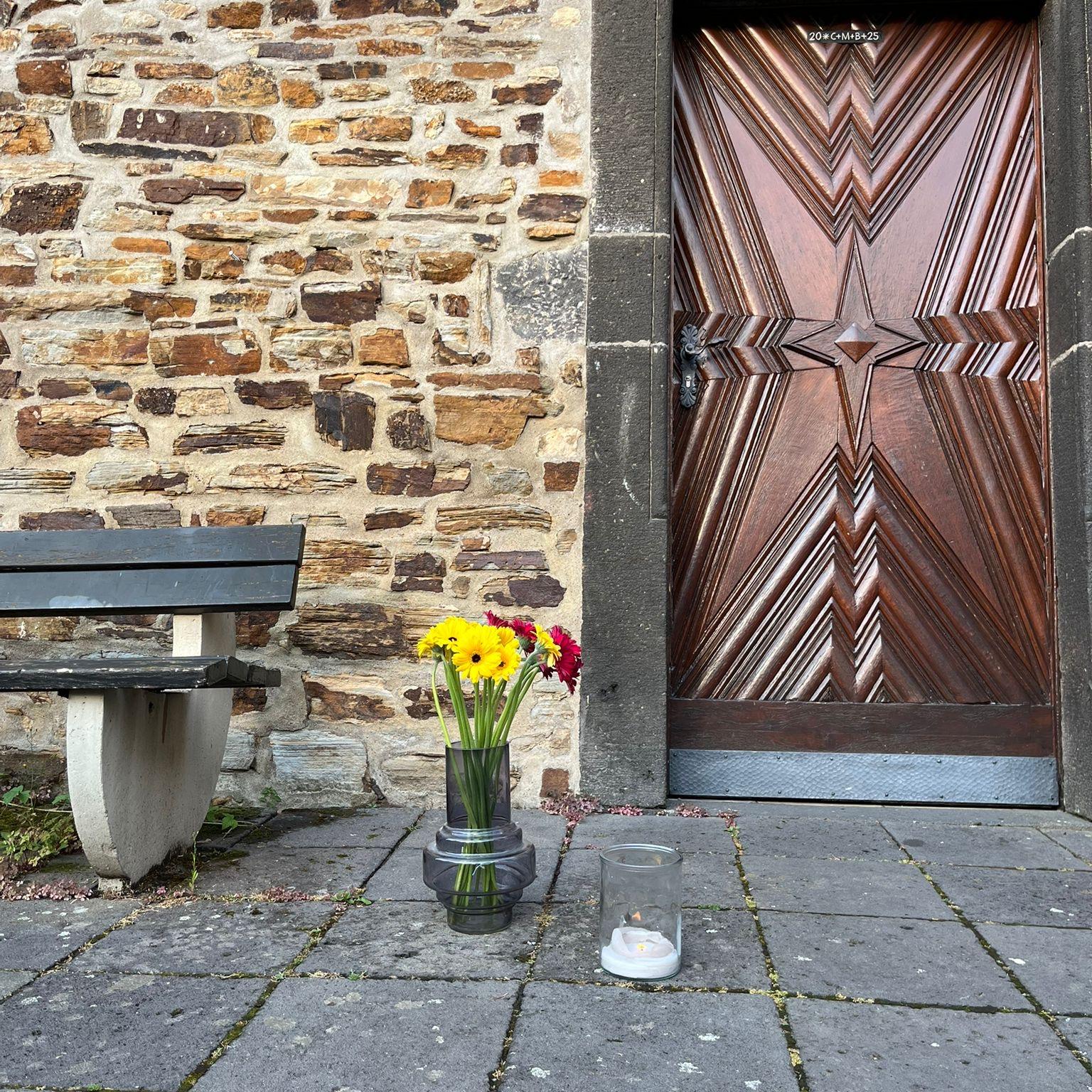Blumenstrauß steht auf dem Boden vor Kirchentür