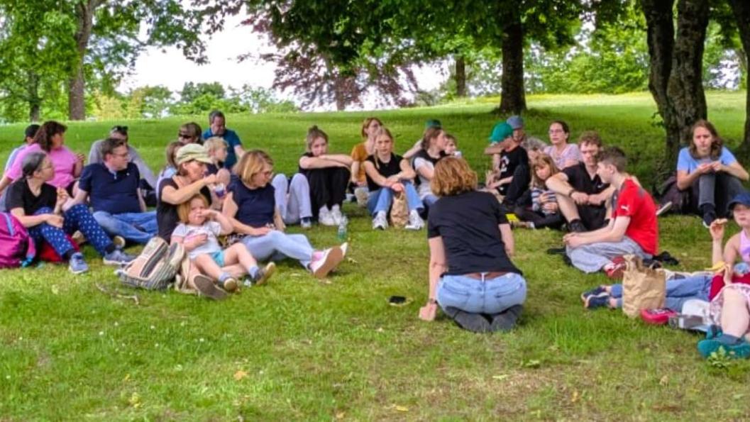 Ein Teil der Gruppe genießt den kühlenden Schatten im Freudenberger Kurpark nach einer hitzigen Stadtrallye.