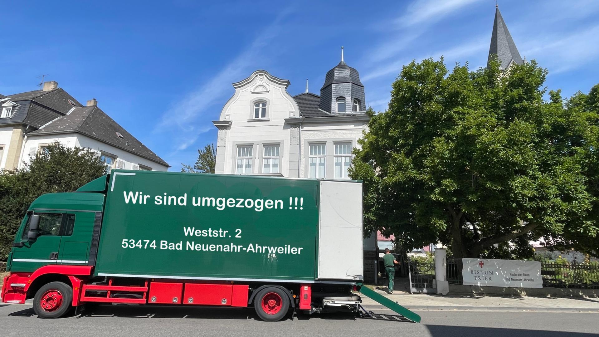 Gebäude Weststr. 2 mit grünem Umzugs-LKW und Aufschrift: 'Wir sind umgezogen'